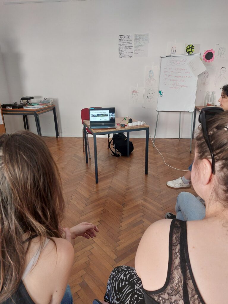 Skupina oseb v prostoru sedi in sodeluje pri aktivnosti.